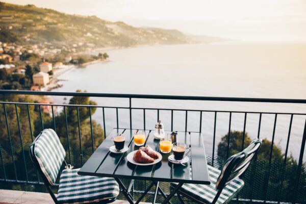 Delicious breakfast with coffee, pastry, and orange juice served on the balcony with sea view.